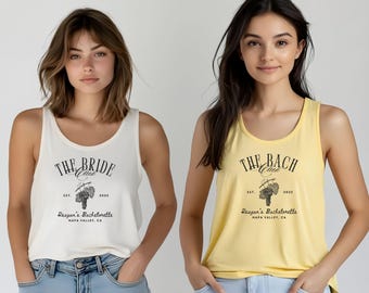 May include: Two tank tops, one cream and one yellow, with black text and graphics. The cream tank top reads "THE BRIDE CLUB" with "EST. 2025" and "Reagan's Bachelorette NAPA VALLEY, CA". The yellow tank top reads "THE BACH CLUB" with similar text.