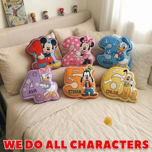 May include: Six plush number-shaped pillows featuring Disney characters: Mickey Mouse on a red 1, Minnie Mouse on a pink polka-dot 2, Donald Duck on a blue 3, Daisy Duck on a purple 4, Goofy on an orange 5, and Pluto on a yellow 6, each with a name.