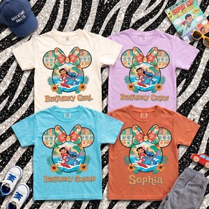May include: Four short-sleeve t-shirts in cream, light purple, light blue, and orange, each featuring a graphic of Lilo and Stitch inside a Mickey Mouse ear silhouette with a floral bow, with text reading Birthday Girl, Birthday Crew, Birthday Squad, and Sophia.