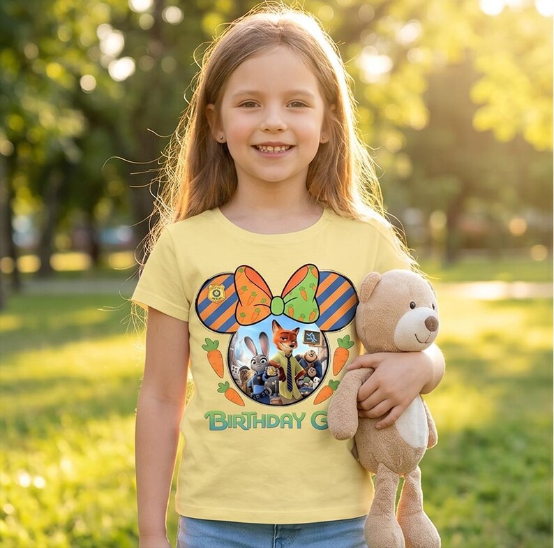 K&ouml;nnte beinhalten: Ein hellgelbes Kurzarm-T-Shirt mit einer Grafik aus Mausohren mit einer karottenmuster-Schleife, einem Zootopia-Charakterdruck, dem gr&uuml;nen Schriftzug "BIRTHDAY GIRL" sowie Illustrationen von orangefarbenen Karotten.