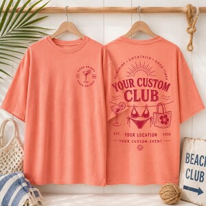 May include: A coral-colored t-shirt featuring a small graphic on the front left chest with a cocktail glass and the text Good Drinks Good Friends Est 2024. The back displays a large graphic with the text Your Custom Club, Sunshine, Cocktails, Good Times, Your Location, 2026, and Your Custom Event, alongside illustrations of a cocktail, a bikini, and a tote bag.