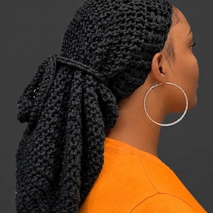 May include: A black crocheted hair snood or bonnet featuring a textured, open-knit pattern. The head covering has a gathered, pouch-like design at the back with a matching crocheted tie detail, providing a secure fit for long hair.