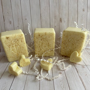 May include: Three bars of natural soap with a leaf design, packaged in white shredded paper and surrounded by small heart-shaped soaps.