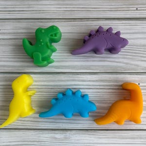 May include: Five colorful dinosaur-shaped silicone molds. The molds are green, purple, yellow, blue, and orange.
