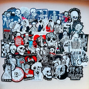 Pode incluir: Uma coleção de adesivos coloridos com vários desenhos de esqueletos. Os adesivos têm frases e ditados diferentes, incluindo "Pretty Fly for a Dead Guy", "Feelin' Good's Good Enough", "Leave Me Alone" e "Skeleton Squad".