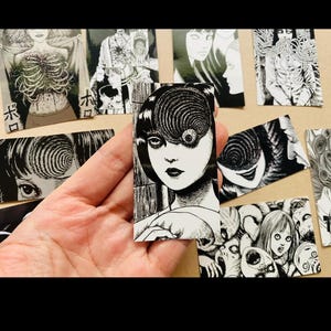 Może przedstawiać: Zestaw czarno-białych naklejek przedstawiających postać z okiem w kształcie spirali i innymi motywami grozy. Naklejki są wydrukowane na białym papierze i mają błyszczące wykończenie.