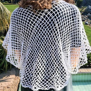 May include: White crochet top with a loose, open-weave design. The top has a wide, rounded neckline and short, flared sleeves.