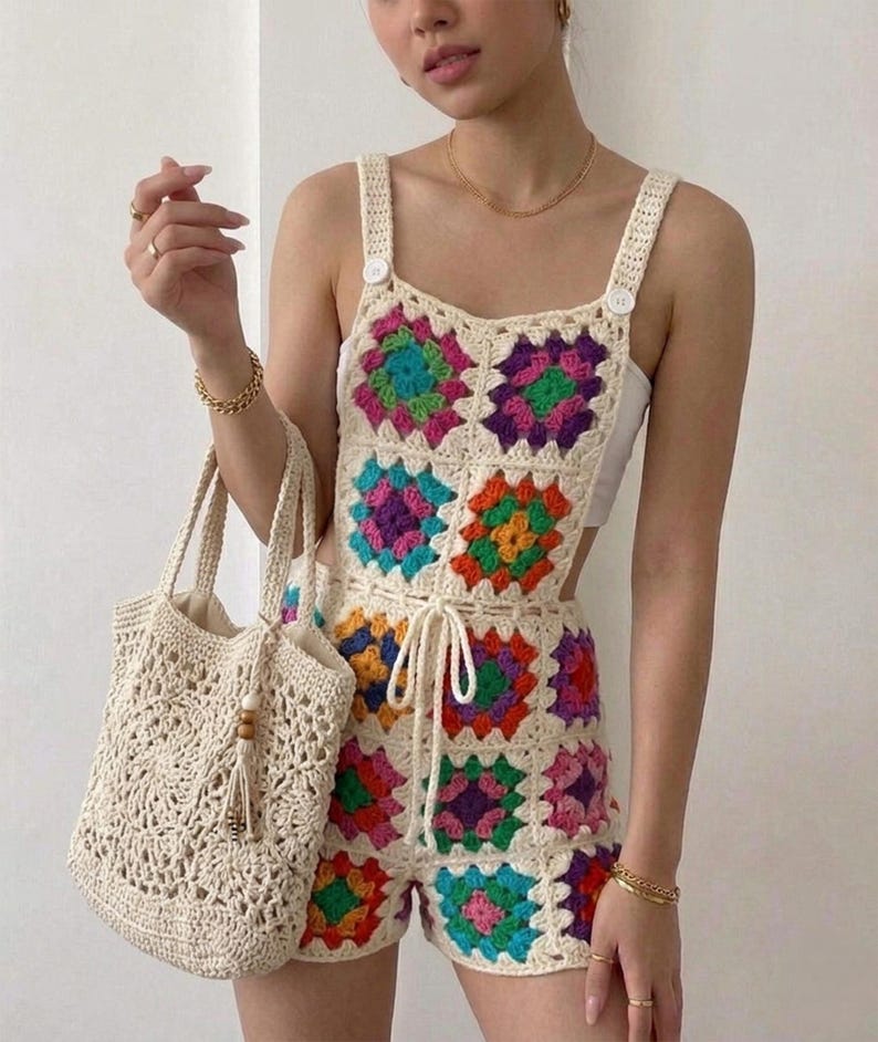 May include: A cream-colored crochet romper with colorful square patterns. The romper features a drawstring waist and buttoned straps. A matching crochet tote bag with a tassel is also visible.
