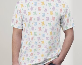 May include: A white t-shirt featuring a repeating pattern of pastel coloured teddy bears. The bears are in various shades of pink, blue, green, and yellow.