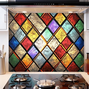 May include: A colorful stained glass kitchen backsplash with a diamond pattern in shades of red, yellow, green, blue, and purple. The backsplash is behind a black gas stove with four burners.