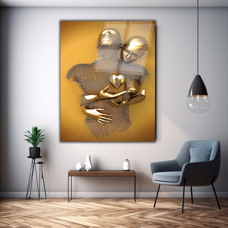 May include: A gold-toned sculpture of two figures embracing, one with a chainmail-like torso, holding a heart-shaped object. The sculpture is set against a yellow background.