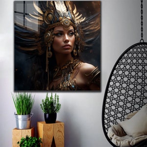 May include: A woman with dark hair and dark eyes wears a headdress with feathers and gold accents. She is wearing a gold necklace and other jewelry. The background is dark and blurry.