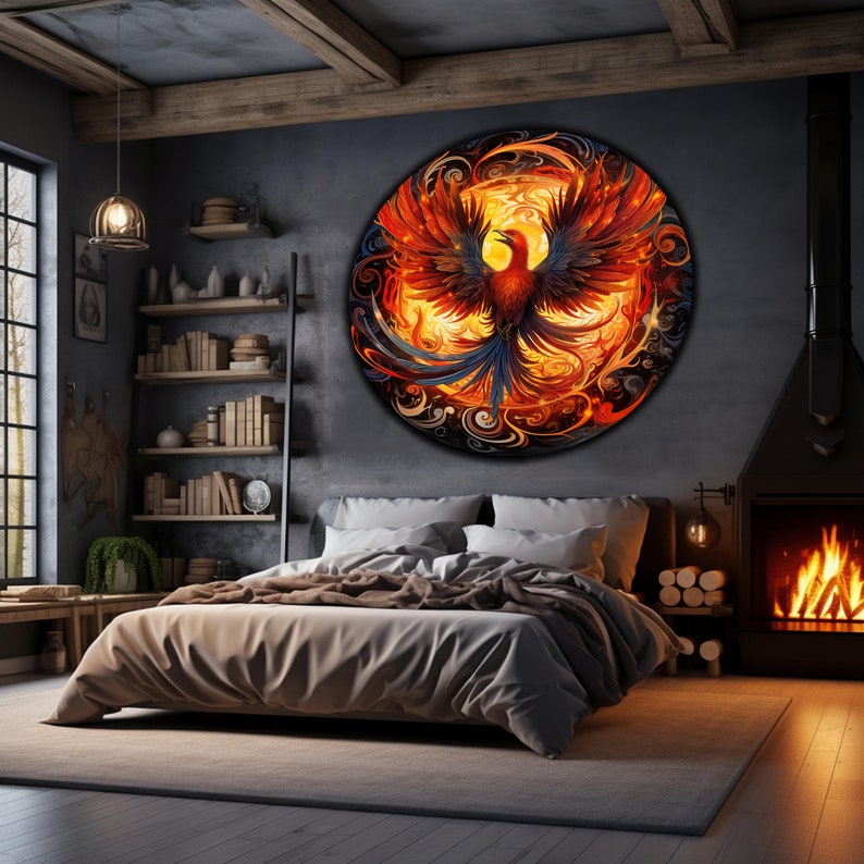 May include: A bedroom interior with a large circular wall art featuring a phoenix rising from flames. The phoenix is depicted in shades of orange, red, and yellow, with a blue tail. The wall art is set against a dark gray wall, and the room is furnished with a bed, a bookshelf, and a fireplace.