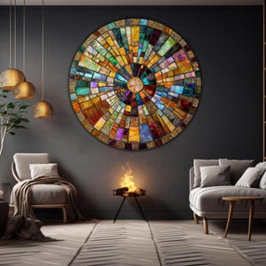 May include: A large, round, colorful mosaic wall art piece with a circular pattern of various colored glass tiles. The art piece is hanging on a dark gray wall in a living room setting with a fireplace and two couches.
