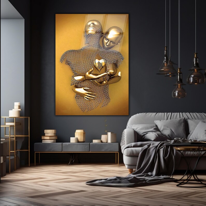 May include: A gold-toned abstract sculpture of two figures embracing, with a heart shape in the center. The sculpture is set against a yellow background.