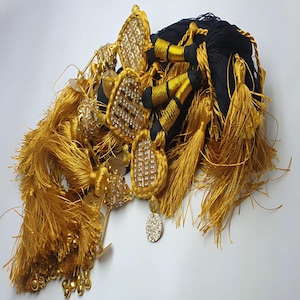 May include: A collection of gold tassel trim with black cord and decorative embellishments. The tassels are made of soft, fluffy fibers and have a luxurious look.