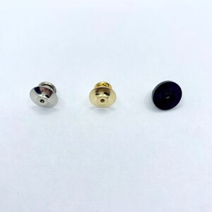 Peut inclure: Trois dos de broche en m&eacute;tal argent&eacute;, dor&eacute; et noir.