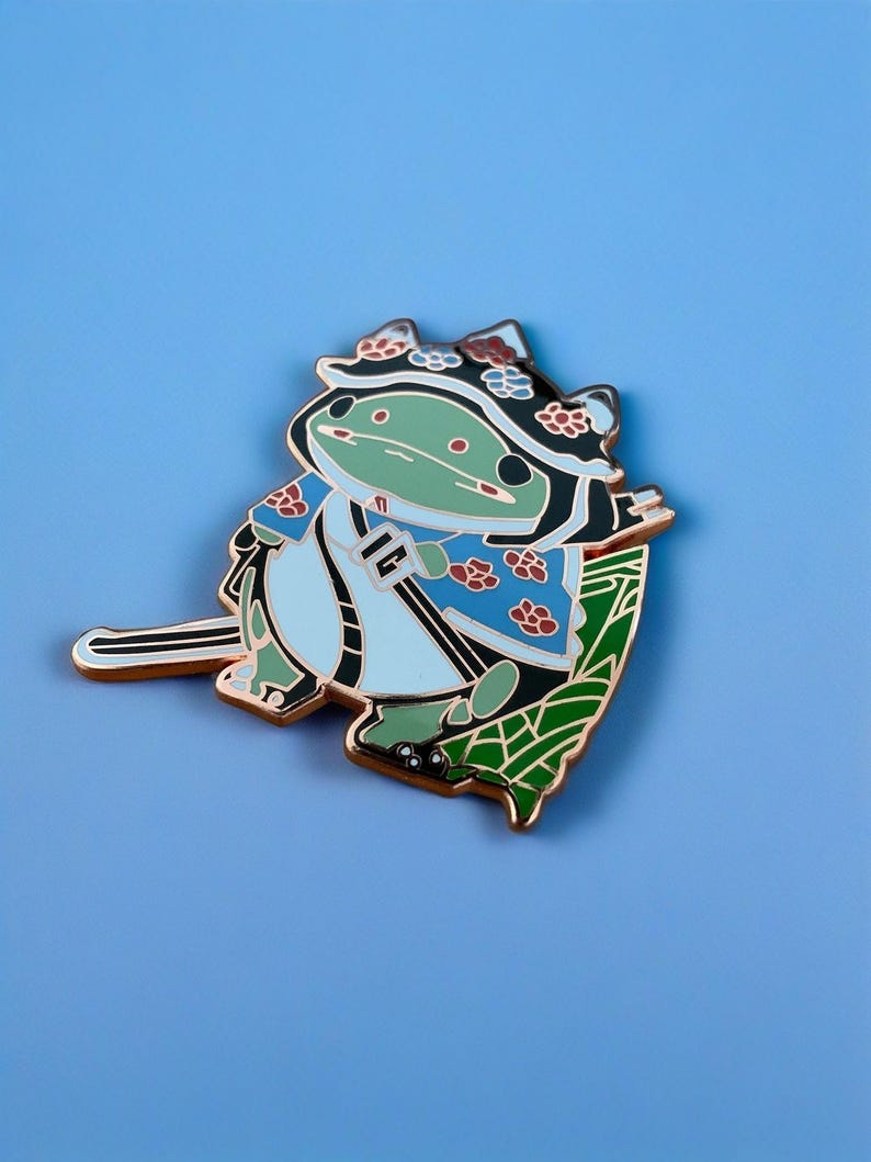 Peut inclure: Une grenouille verte portant un kimono bleu et blanc avec une feuille verte et des fleurs sur la t&ecirc;te. La grenouille tient une &eacute;p&eacute;e noire et se tient sur une feuille verte. La grenouille est un personnage de dessin anim&eacute; et a un design mignon et fantaisiste.