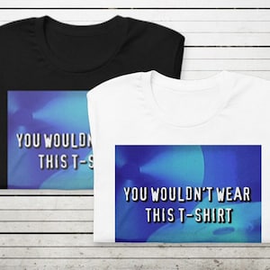 Può includere: Due t-shirt, una nera e una bianca, con lo stesso design. Il design è un'immagine blu e bianca con il testo "You wouldn't wear this t-shirt".