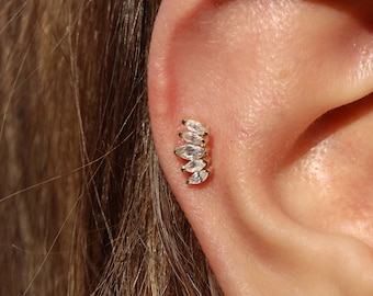 May include: A gold ear cuff with five clear marquise-shaped stones set in a row.