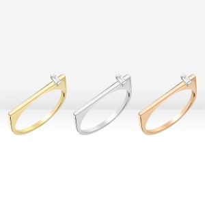 May include: Three minimalist rings with a single diamond set in a rectangular band. The rings are available in gold, silver, and rose gold.