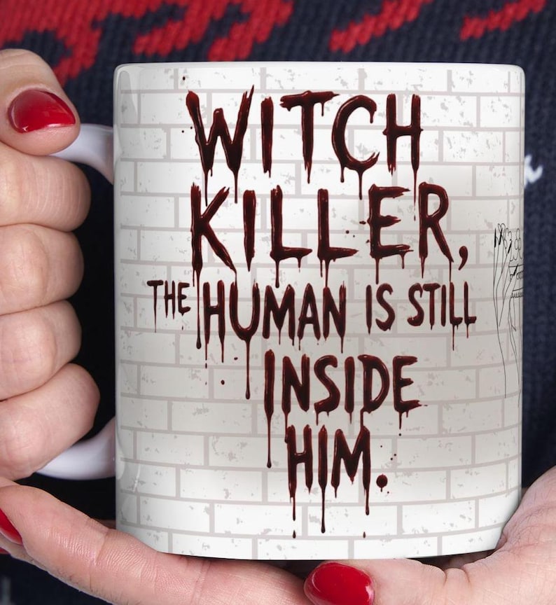 Pu&ograve; includere: Tazza in ceramica bianca con la scritta "WITCH KILLER, THE HUMAN IS STILL INSIDE HIM." in rosso scuro gocciolante. Lo sfondo presenta un disegno a muro di mattoni bianchi. La tazza &egrave; tenuta da una persona con lo smalto rosso.