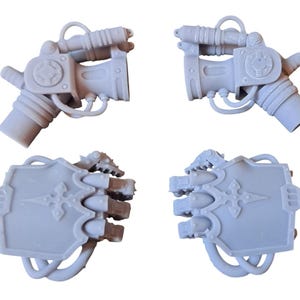 Könnte beinhalten: Vier graue Plastikteile für einen Modellbausatz. Zwei Teile sind eine Hand mit einer klauenartigen Greiffunktion und zwei Teile sind eine Waffe mit einem langen Lauf und einer runden Basis.