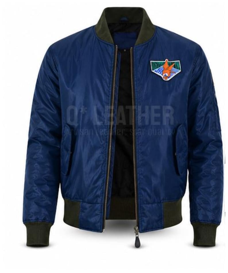 May include: A navy blue bomber jacket featuring a dark olive green ribbed collar, cuffs, and hem. The jacket has a front zipper closure and a colorful embroidered patch on the left chest depicting an orange character. The text Q*LEATHER is visible.