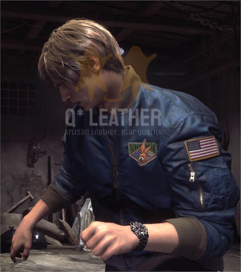 May include: A dark blue bomber jacket featuring a front zipper, brown ribbed cuffs, and a zippered utility pocket on the left sleeve. An American flag patch is on the sleeve, and a triangular patch with a graphic design is on the chest.