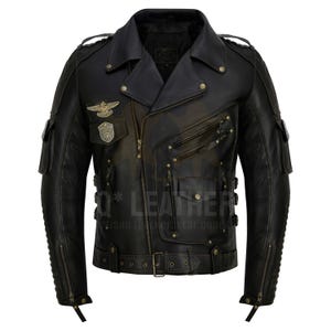 Op de afbeelding: Zwarte leren motorjas met een asymmetrische ritssluiting. Voorzien van meerdere zakken, decoratieve metalen studs en een riem in de taille. Er zijn patches zichtbaar op de borst en schouders. De jas heeft een distressed, vintage uitstraling.