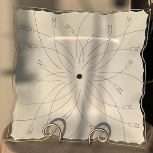 May include: A frosted glass ceiling light fixture with a square shape and a wavy edge. The glass has a floral design etched into it.