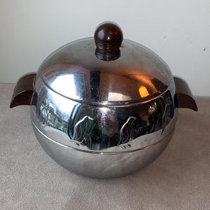May include: A silver ice bucket with a brown lid and handles. The bucket is decorated with penguin silhouettes.