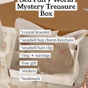May include: A Sea Fairy World Mystery Treasure Box, open to reveal a crystal bracelet, seashell bag charm, hair clip, ring, earrings, stickers, and a bookmark. The box is lined with tissue paper and surrounded by decorative beads.