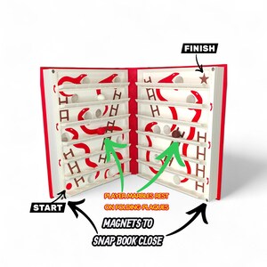 May include: A red and white marble game in the shape of a book. The game has a start and finish, with the text "PLAYER MARBLES REST ON FOLDING PLAQUES" and "MAGNETS TO SNAP BOOK CLOSE". The game is designed to be folded.