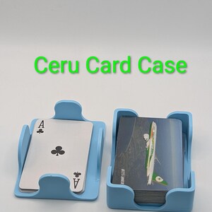 May include: Two light blue card cases, one holding an Ace of Clubs playing card, the other holding a deck of cards. The text "Ceru Card Case" is above the cases. The cards in the second case have a green and white design.