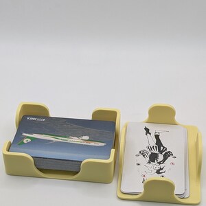 May include: Two light yellow card holders, one containing a stack of cards with an airplane graphic and the text "B777-300ER". The other holder contains cards with a black and white illustration.