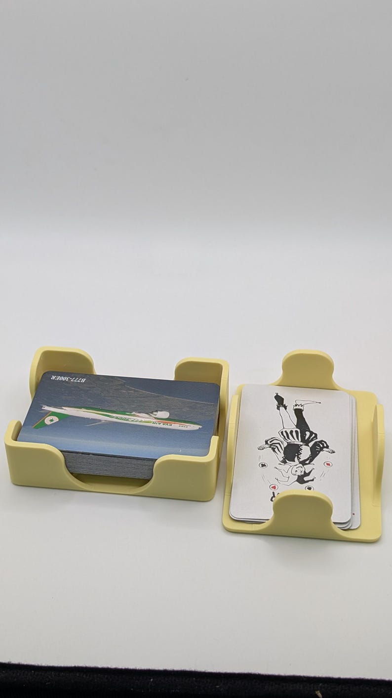 May include: Two light yellow card holders, one containing a stack of cards with an airplane graphic and the text "B777-300ER". The other holder contains cards with a black and white illustration.