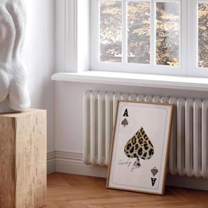 May include: A framed print of an ace of spades playing card with a leopard print design. The text "lucky you" is printed below the card.
