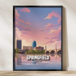 Puede incluir: Impresión artística enmarcada que presenta una ilustración estilizada de Springfield, Missouri, con un cielo al atardecer y reflejo en el agua. La obra de arte incluye el horizonte de la ciudad, un puente y el texto "Springfield Missouri."