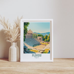 May include: A white framed print with a colorful illustration of an ancient Roman amphitheater in Plovdiv, Bulgaria. The text "Plovdiv, Bulgaria" is printed below the image.