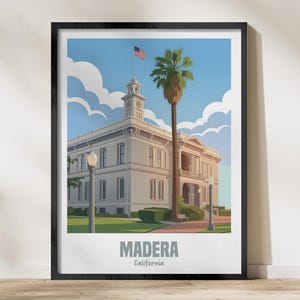 Könnte beinhalten: Ein gerahmter Kunstdruck mit einer stilisierten Illustration des Madera County Courthouse in Kalifornien. Das Kunstwerk zeigt ein weißes Gebäude mit einem Uhrturm, einer amerikanischen Flagge und einer hohen Palme vor blauem Himmel. Das Wort "MADERA" ist darunter gedruckt.