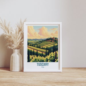 Könnte beinhalten: Ein weiß gerahmter Druck mit einer farbenfrohen Illustration einer toskanischen Landschaft. Der Druck zeigt sanfte Hügel, Weinberge und ein kleines Dorf in der Ferne. Der Text "Tuscany, Italy" ist unten auf dem Druck gedruckt.