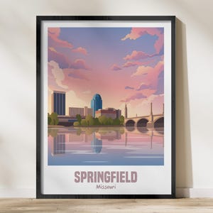 Puede incluir: Impresión artística enmarcada que presenta una ilustración estilizada de Springfield, Missouri, al atardecer. La obra representa un paisaje urbano con un río, un puente y un cielo colorido en tonos de rosa, morado y azul. La palabra "Springfield" está impresa en la parte inferior.