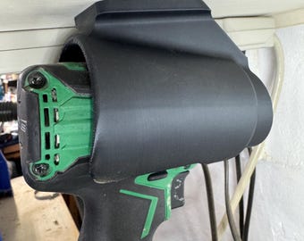 May include: A black 3D printed wall mount for a cordless drill. The mount is designed to hold the drill by the handle and the battery pack. The drill is green and black.