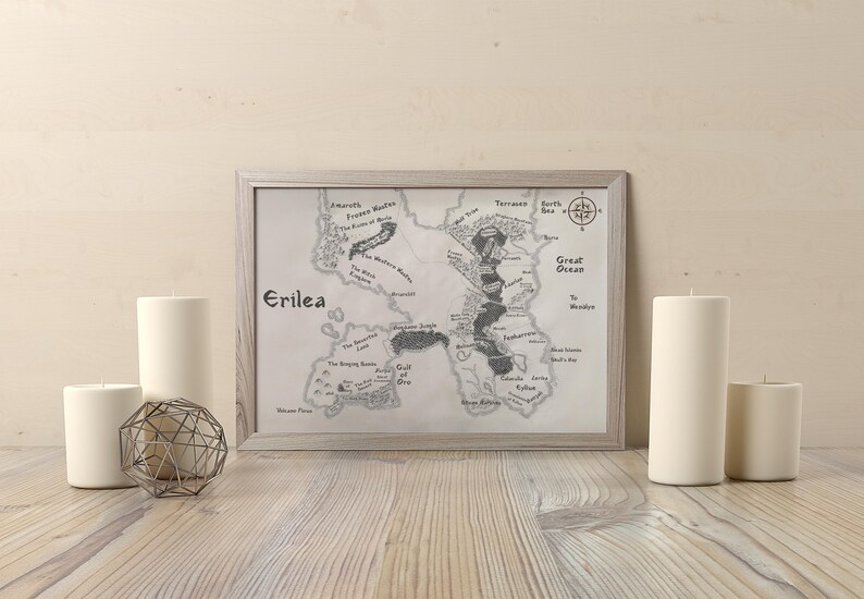 May include: A framed black and white map of the fictional land of Erilea. The map is surrounded by a white mat and a light gray frame. The map shows a large island with various rivers, lakes, and mountains. The text "Erilea" is printed in the top left corner of the map.