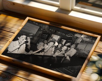 May include: A rectangular wooden frame containing a black and white photograph of a group of people sitting at a bar counter. The individuals are holding small glasses and bottles while gathered in a dimly lit indoor setting with a ceiling fan.