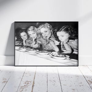 Puede incluir: Cuatro mujeres en una fotografía en blanco y negro están sentadas a una mesa y comiendo espaguetis. Todas sonríen y disfrutan de su comida.