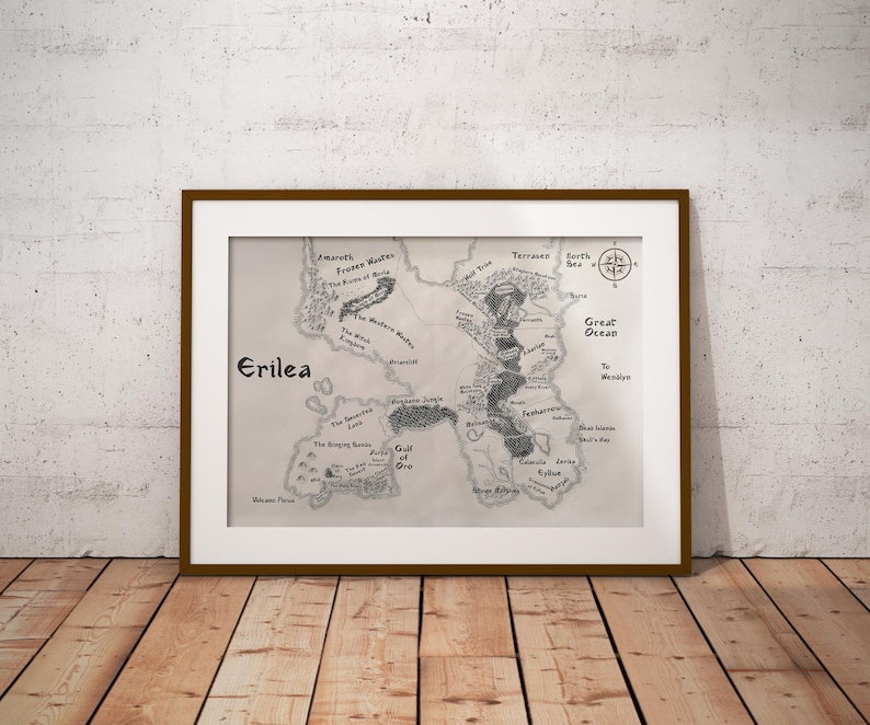 May include: A black and white map of the fictional land of Erilea. The map shows various geographical features, including mountains, forests, rivers, and lakes. The map is framed in a brown wooden frame.