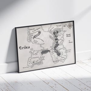 May include: A black and white map of the fictional land of Erilea. The map shows various geographical features, including mountains, rivers, forests, and a large ocean. The map is framed in a black frame.