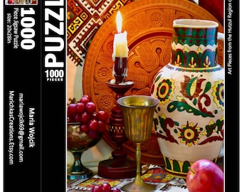 May include: A still life featuring a wooden platter with intricate carvings, a lit candle, a pitcher with floral designs, a chalice, and grapes. The scene is set on a table with a white tablecloth and a red and white patterned rug.